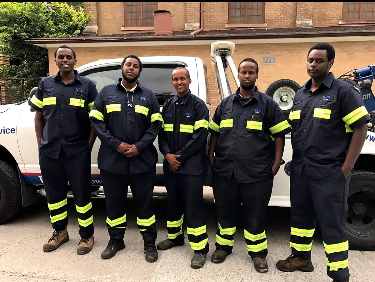 Five UBK Towing drivers in uniform standing in front of a tow truck