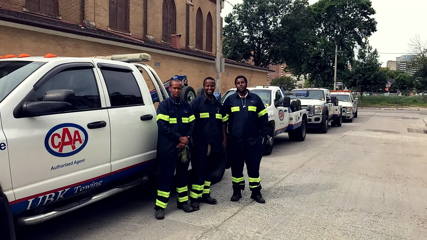 UBK Towing drivers standing beside a line of CAA authorized tow trucks